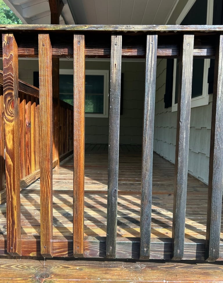 Wooden fence gate showing weathered posts from warm brown on left to gray-silvered on right, with glass doors visible behind