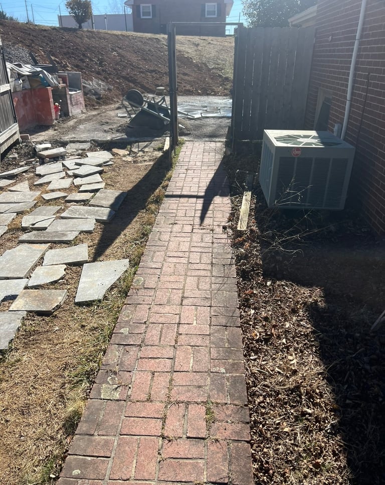 Backyard brick pathway with metal posts, wooden structures, and construction materials scattered on the ground