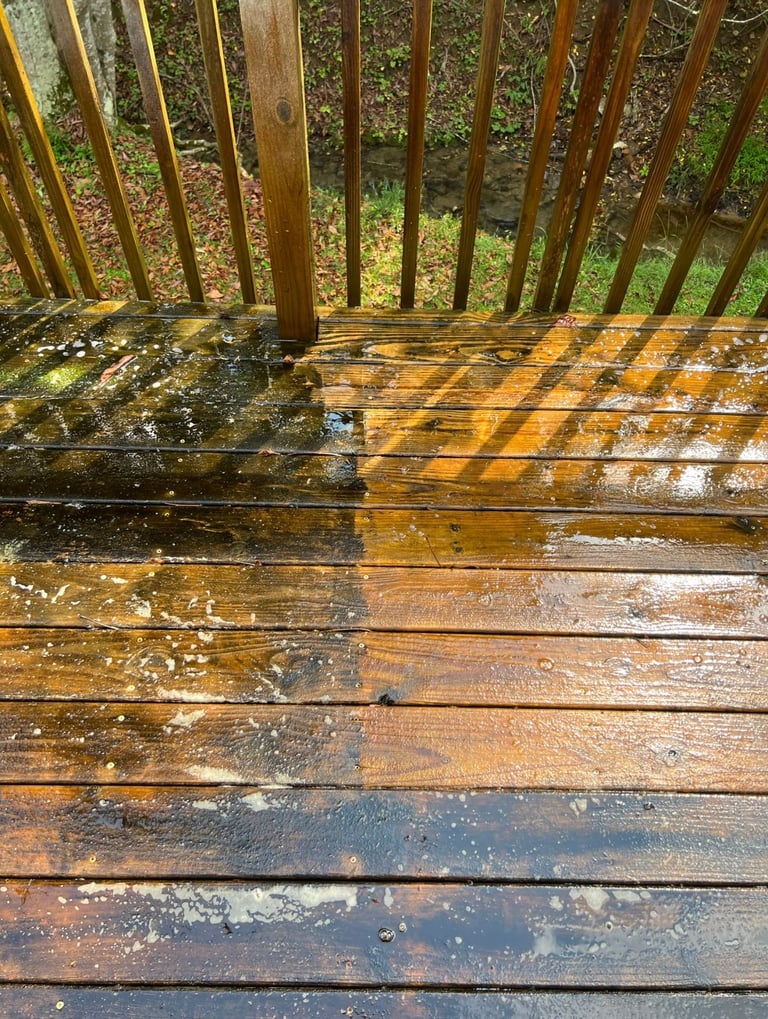 Wet wooden deck with rain-soaked boards and vertical balusters, showing shadow patterns and moisture reflections
