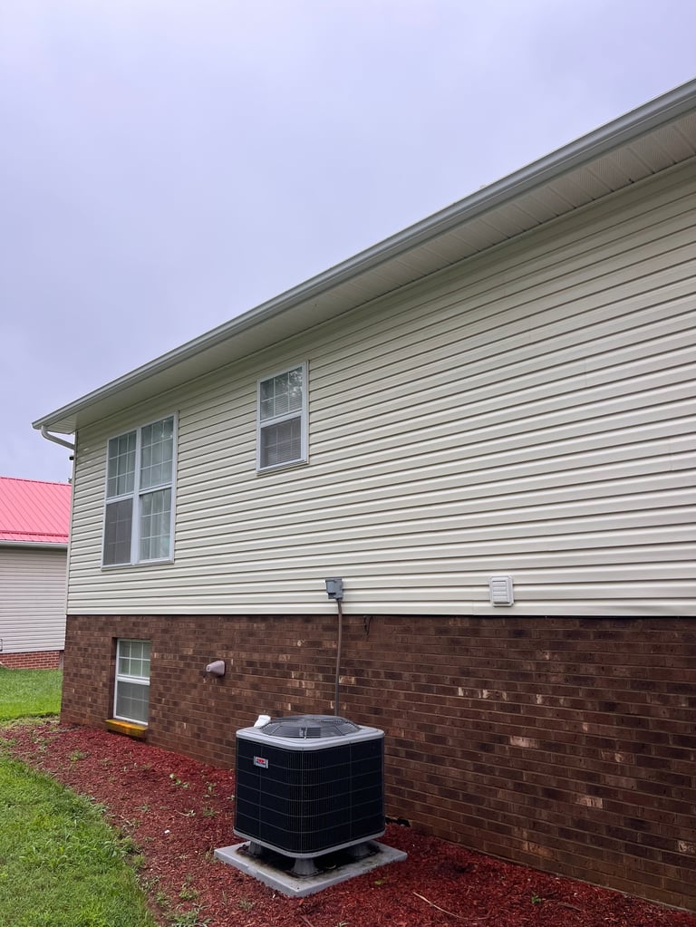 Exterior of a two-story house with vinyl siding, brick foundation, and an HVAC unit in the front yard with red mulch landscaping